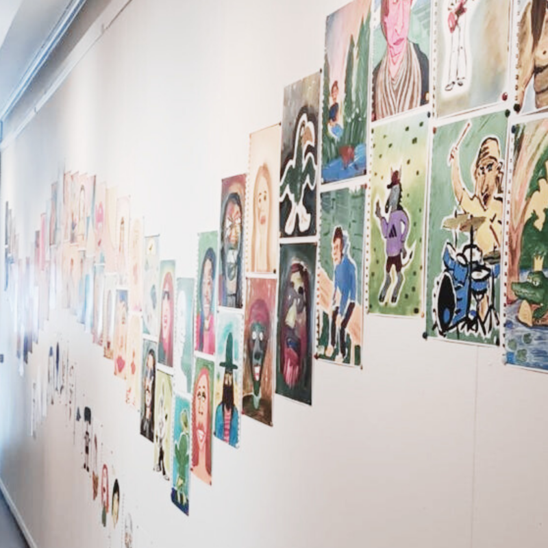 Kuva Jukka Nissisen taidenäyttelystä. Värikkäitä tussipiirroksia seinällä kaarevassa muodossa
